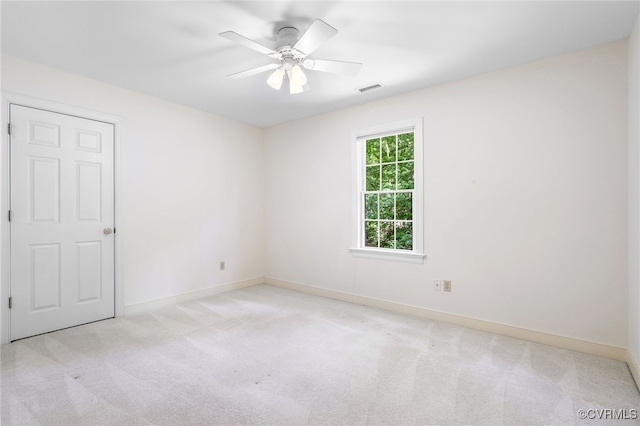 carpeted empty room with a ceiling fan and baseboards