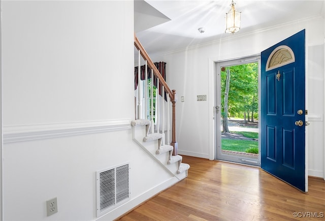 entryway with stairway, ornamental molding, wood finished floors, and baseboards