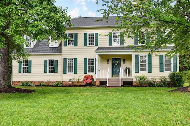 colonial inspired home featuring a shingled roof, a porch, and a front yard
