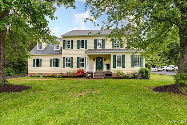 colonial-style house with covered porch, roof with shingles, a front yard, and crawl space