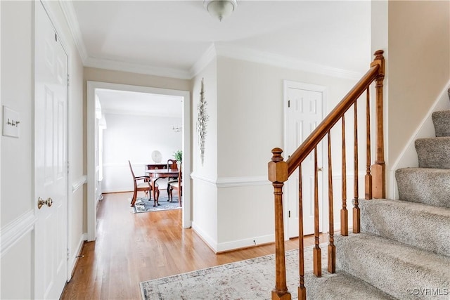 foyer featuring crown molding, light wood-style floors, stairway, and baseboards