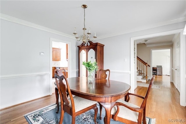 dining area with a notable chandelier, crown molding, light wood-type flooring, and stairs