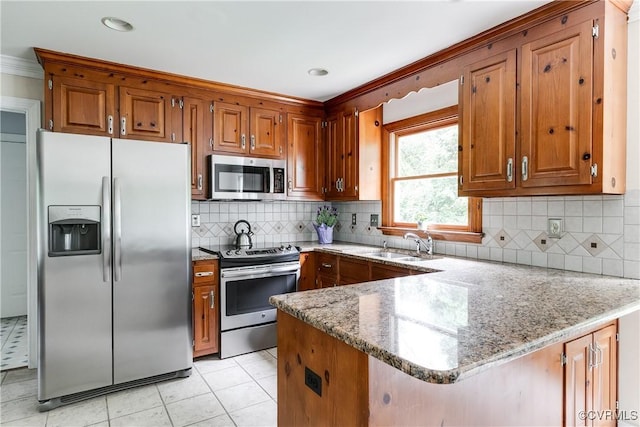 kitchen with brown cabinets, a peninsula, and appliances with stainless steel finishes