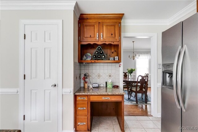 bar featuring light tile patterned floors, stainless steel fridge, a notable chandelier, crown molding, and tasteful backsplash
