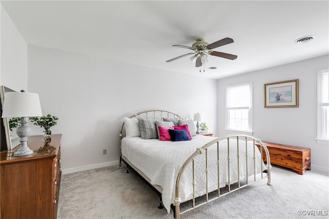 bedroom with light colored carpet, visible vents, and multiple windows