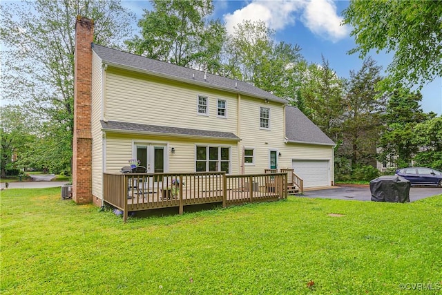 rear view of property featuring cooling unit, a chimney, a wooden deck, a yard, and driveway