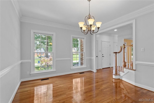 unfurnished dining area featuring ornamental molding, a notable chandelier, visible vents, and wood finished floors