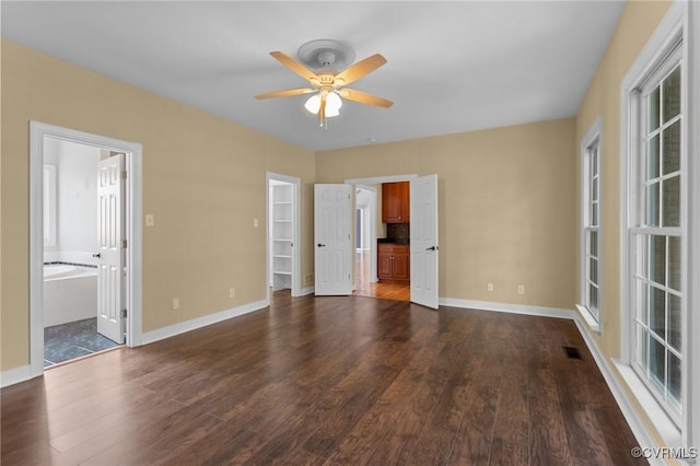 unfurnished bedroom featuring baseboards, ensuite bath, and dark wood-type flooring