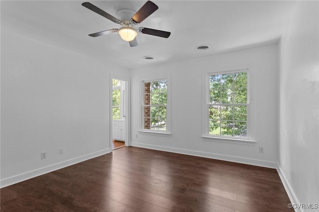 spare room featuring baseboards, visible vents, and dark wood-style floors