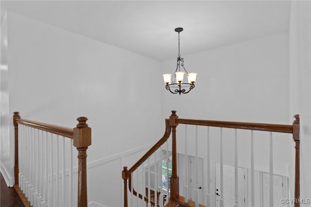 stairs featuring a chandelier and wood finished floors