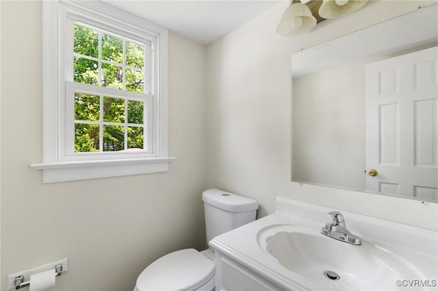 half bath featuring vanity, toilet, and a wealth of natural light