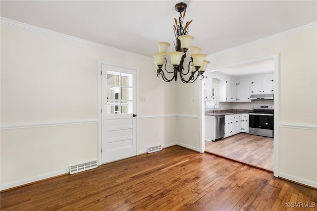 unfurnished dining area featuring a wealth of natural light, a notable chandelier, visible vents, and hardwood / wood-style flooring
