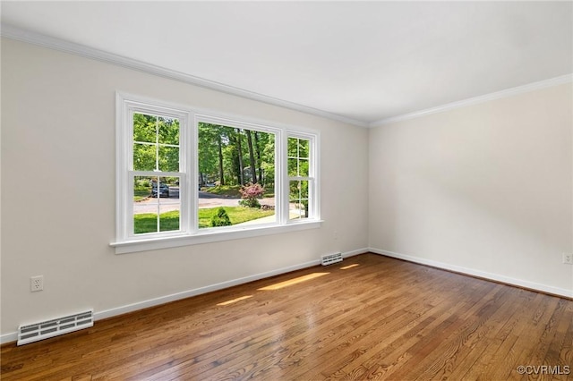 spare room featuring crown molding, visible vents, baseboards, and hardwood / wood-style floors
