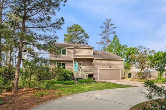 traditional-style home featuring a garage, driveway, fence, and a front yard