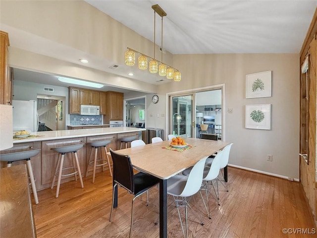 dining area with baseboards, light wood-style flooring, and visible vents