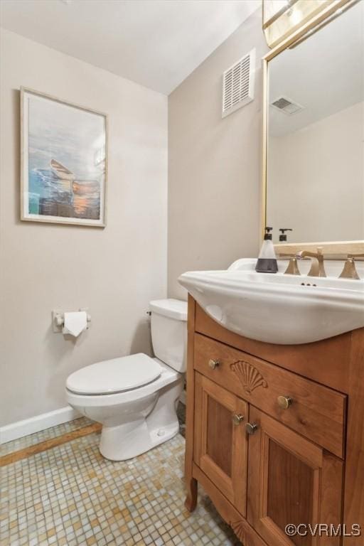 half bathroom featuring vanity, toilet, baseboards, and visible vents