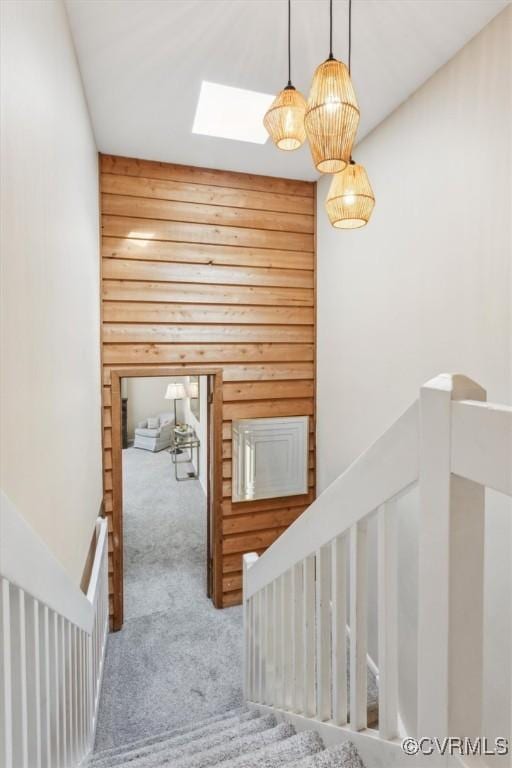 stairs featuring wood walls, a skylight, and carpet floors