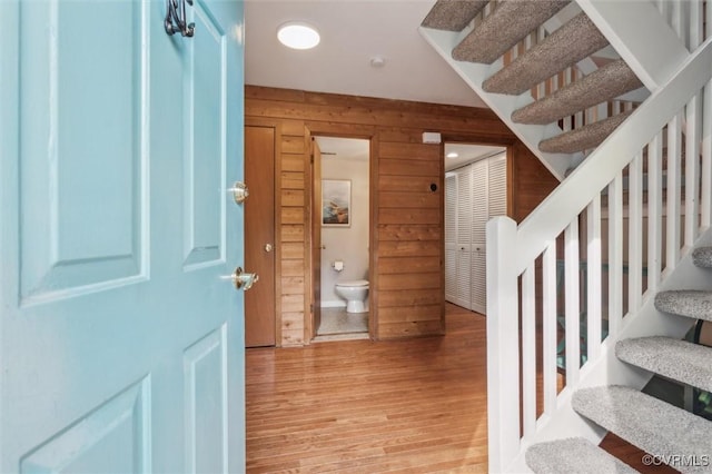 stairway featuring wood walls and wood finished floors