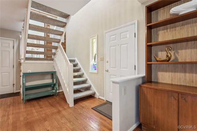 entrance foyer with light wood-type flooring, stairway, and baseboards