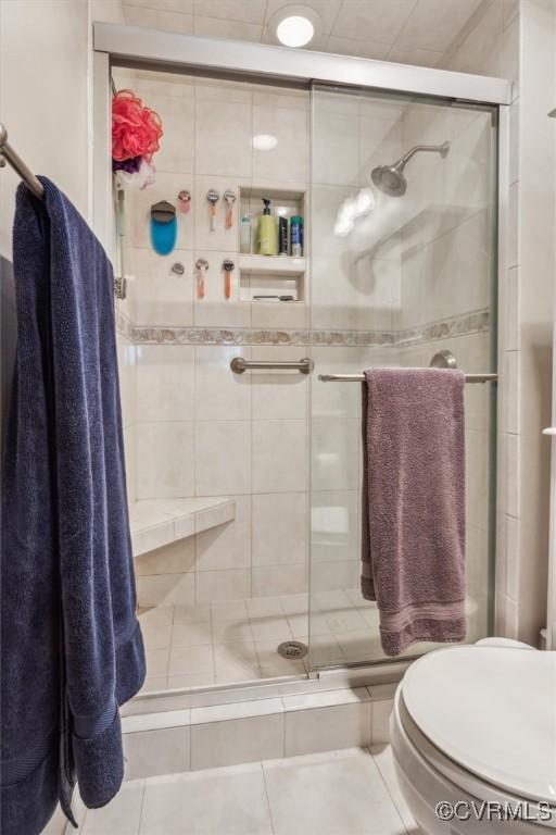 full bath with a stall shower, toilet, and tile patterned floors