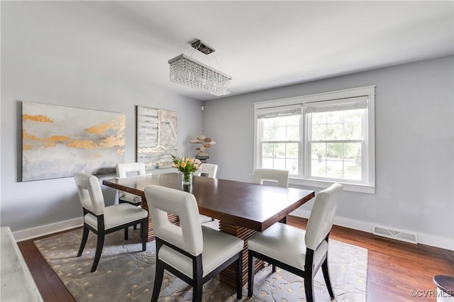 dining area with baseboards, visible vents, and wood finished floors