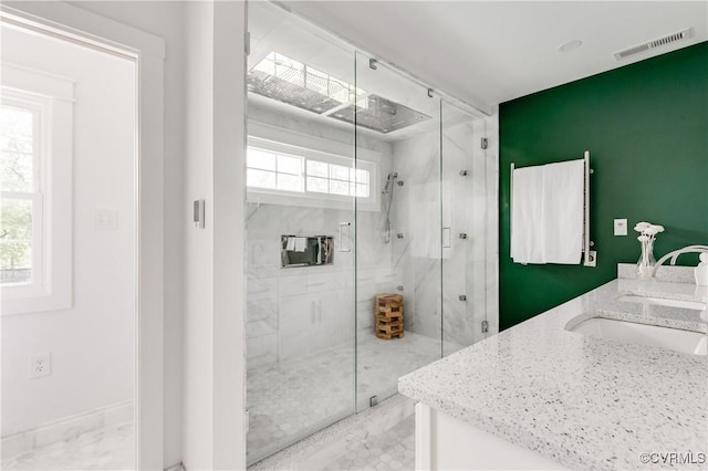 bathroom with marble finish floor, a sink, a marble finish shower, and visible vents