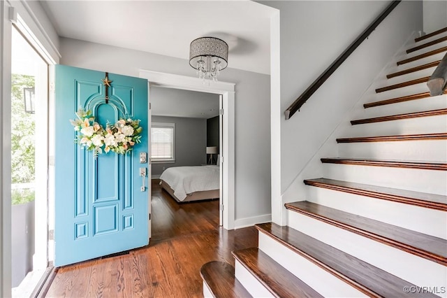entryway with an inviting chandelier, stairs, a wealth of natural light, and wood finished floors