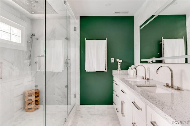 full bathroom featuring double vanity, visible vents, a marble finish shower, and a sink