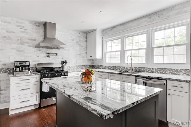 kitchen with a sink, wall chimney exhaust hood, tasteful backsplash, appliances with stainless steel finishes, and light stone counters
