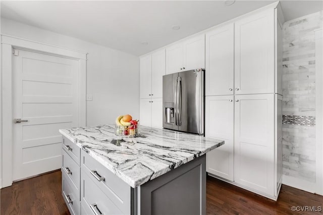 kitchen with white cabinetry, dark wood-style flooring, stainless steel fridge with ice dispenser, and light stone countertops