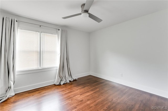 empty room featuring baseboards, a ceiling fan, and dark wood-style floors