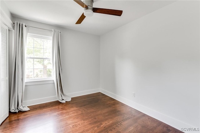 empty room featuring baseboards, dark wood-style flooring, and ceiling fan