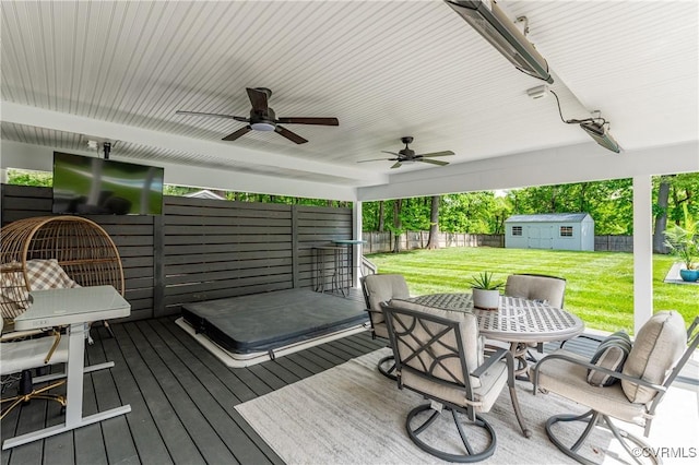 deck featuring a yard, an outdoor structure, a shed, ceiling fan, and a fenced backyard