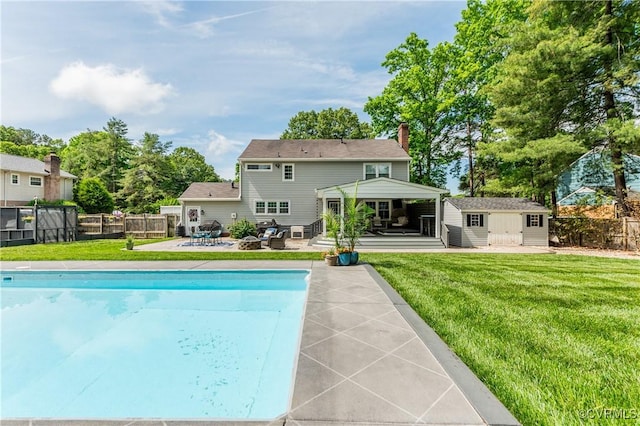 back of property featuring a yard, a chimney, a patio area, and a fenced in pool
