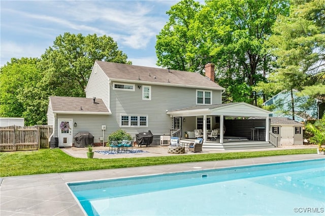 rear view of house with an outdoor fire pit, a patio area, a fenced in pool, and fence
