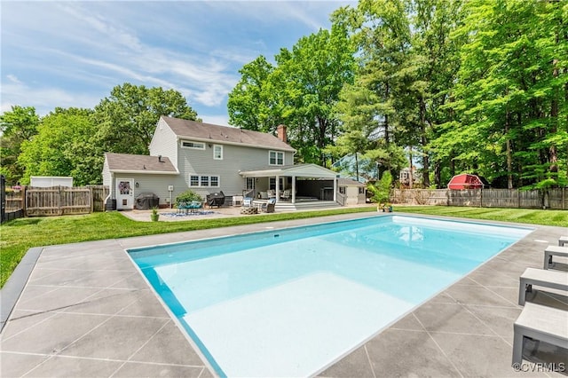 view of pool with a lawn, an outbuilding, a fenced in pool, a patio area, and a fenced backyard