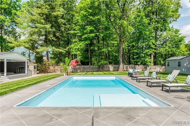 view of pool featuring a yard, a patio area, a fenced backyard, and an outbuilding
