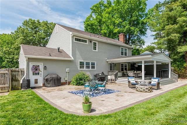 rear view of property with a chimney, a patio area, fence, and a lawn