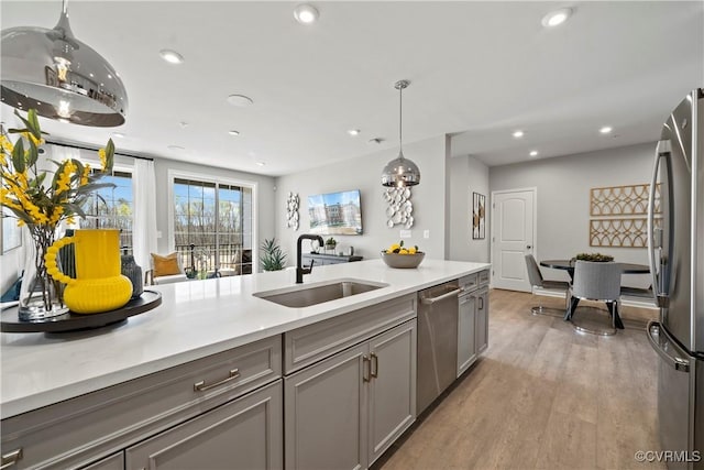 kitchen with a sink, stainless steel appliances, recessed lighting, light countertops, and gray cabinetry