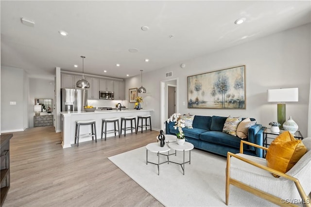living area with baseboards, recessed lighting, light wood-style flooring, and visible vents
