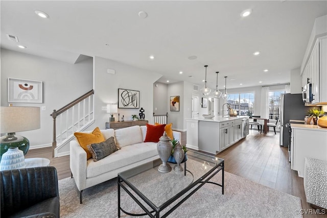living room with wood finished floors, visible vents, recessed lighting, stairway, and baseboards