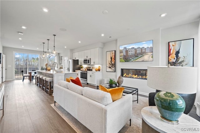living area featuring baseboards, a glass covered fireplace, and recessed lighting