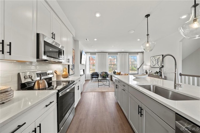 kitchen with a sink, stainless steel appliances, open floor plan, dark wood finished floors, and recessed lighting