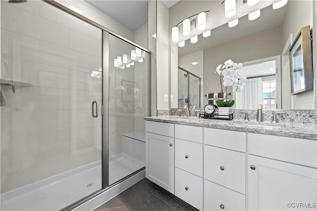 bathroom with a stall shower, tile patterned flooring, double vanity, and a sink