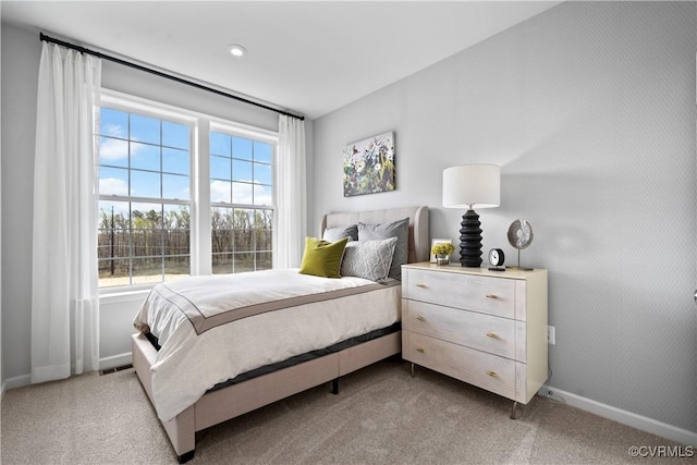 bedroom featuring light colored carpet, multiple windows, and baseboards