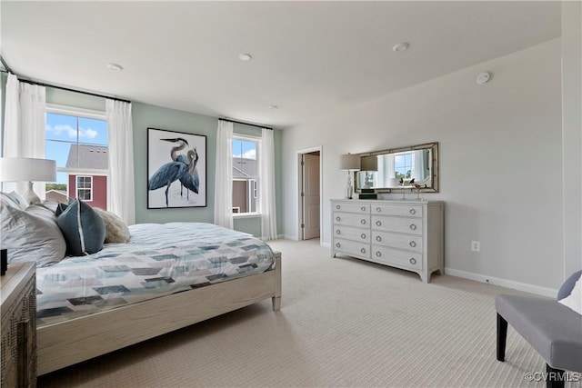 bedroom with light colored carpet, multiple windows, and baseboards
