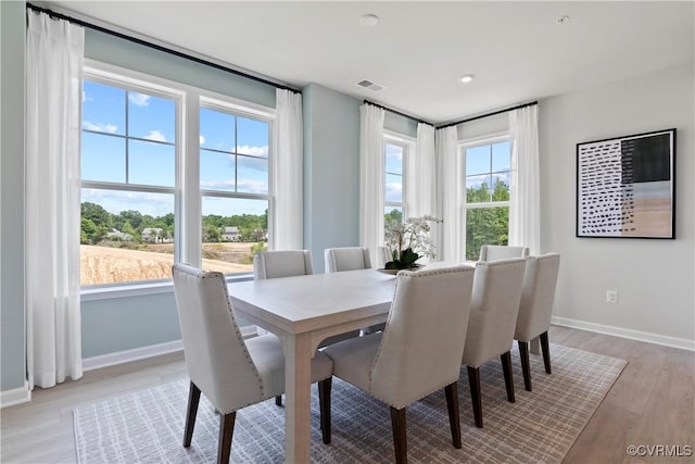dining room with baseboards, light wood-type flooring, and visible vents