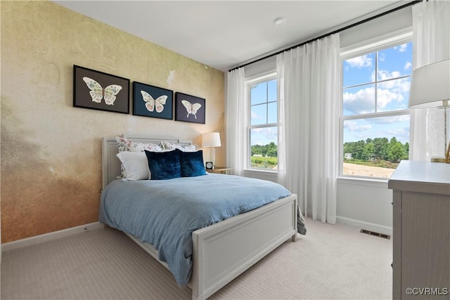 bedroom with baseboards, light carpet, and visible vents