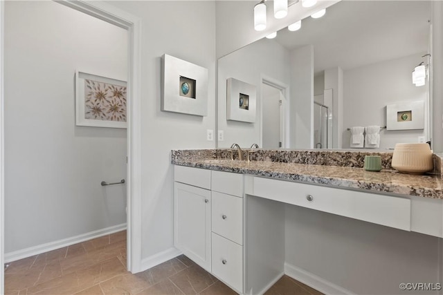 bathroom with baseboards, vanity, and a stall shower