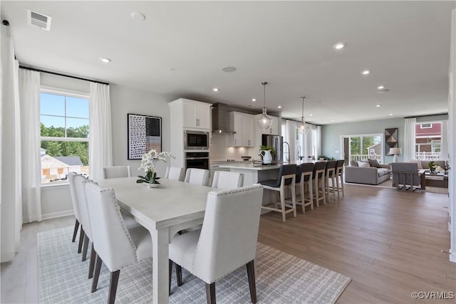dining space with light wood finished floors, visible vents, and recessed lighting